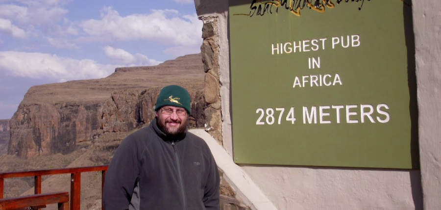 Owner Shelldon Wells stands next to a sign that reads highest pub in africa at 2874 meters