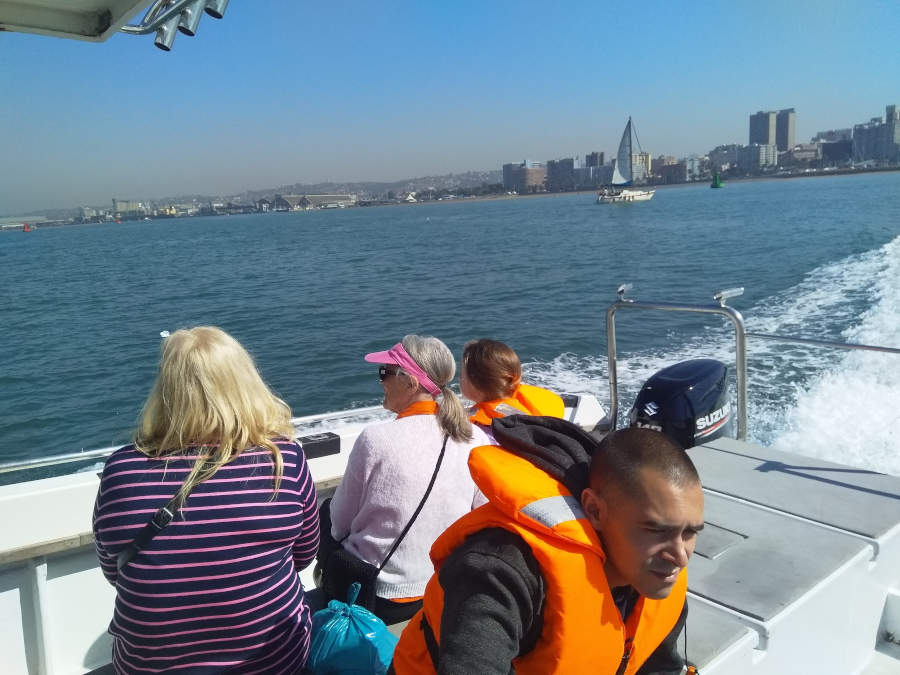 A group of 4 people on a boat leaving a barbor to go whale watching