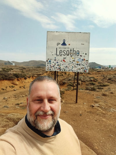 Shelldon (owner of Durban Safaris and Tours) stands in front of the Lesotho signboard at the top of Sani Pass